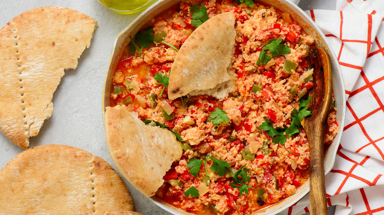 A bowl of Turkish Menemen with bread on a table