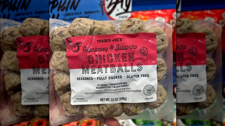 Person's hand holding a shrink-wrapped package of fully cooked Trader Joe's Cranberry & Jalapeño Chicken Meatballs