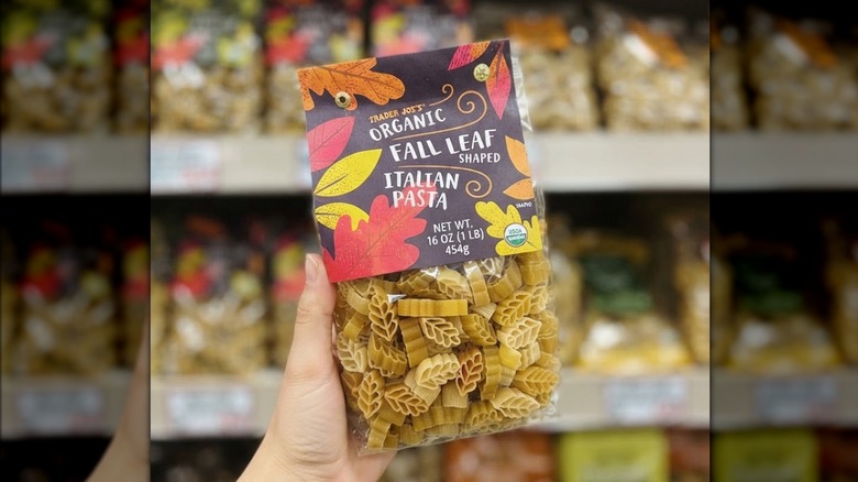 Person's hand holding up a bag of Trader Joe's Organic Fall Leaf Shaped Italian Pasta
