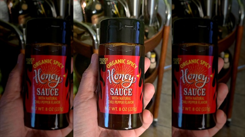 Customer holding bottle of organic spicy honey sauce from Trader Joe's.