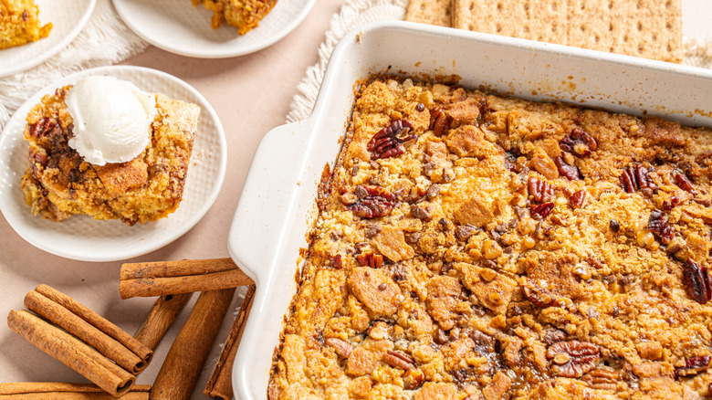 Dump cake with pecans in a baking dish, with slices topped with ice cream on plates