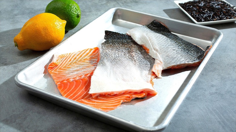 Large pieces of raw, sliced salmon skin on a metal baking sheet