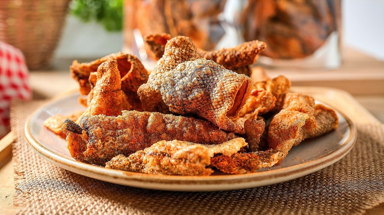 Crispy fried salmon skins on a cream-colored plate over a burlap placemat