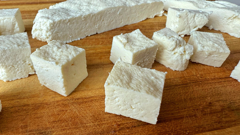 cubes and slabs of paneer on wooden cutting board