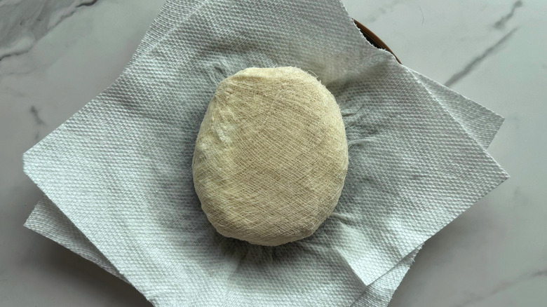wrapped disk of paneer on paper towels