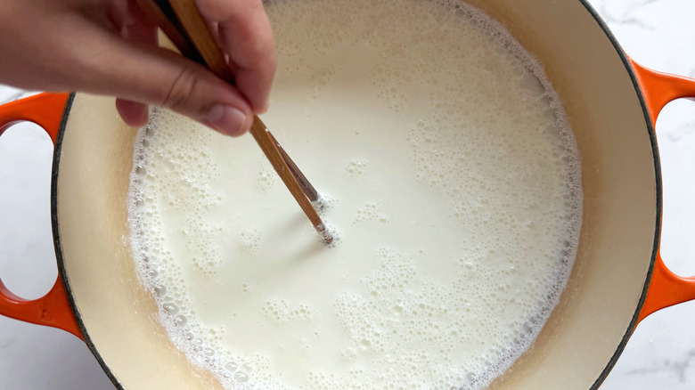pot of milk being stirred with chopsticks