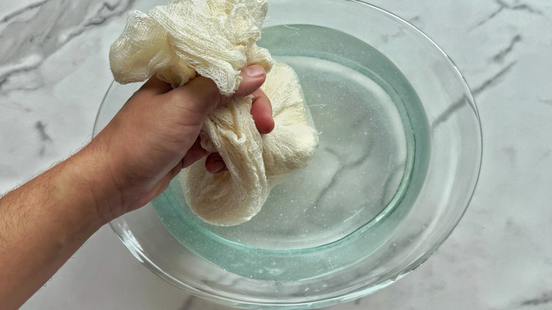 hand dunking bundle into bowl of water