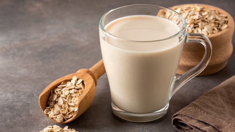 Glass of oat milk with oats in background