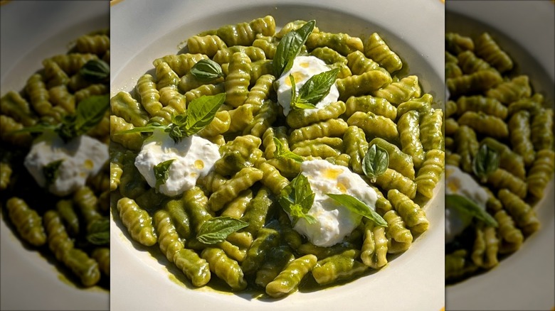 Bowl of pesto pasta with burrata and fresh basil