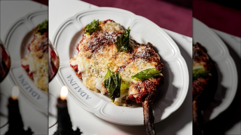 Plate of veal parmigiana topped with fresh basil