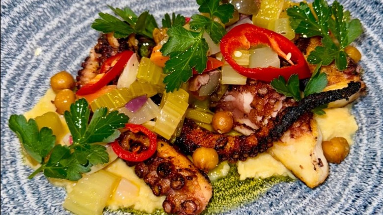 Piccolo Sogno's Polpo Tonnato of grilled octopus, charred frisee, blistered tomatoes, and tuna caper sauce on a decorative blue plate