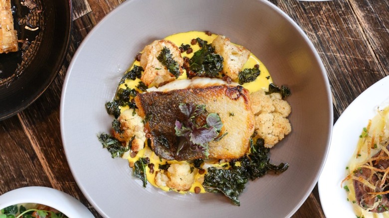 Bowl of white fish with polenta, cauliflower, and kale