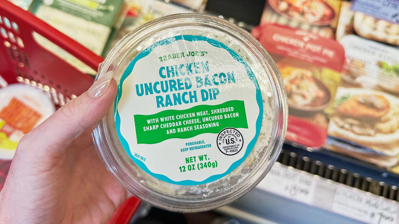 A hand holding a container of chicken bacon ranch dip