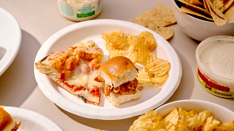 A selection of Trader Joe's tailgating snacks on a paper plate surrounded by chips and dip