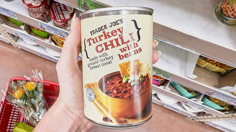 A hand holding a can of turkey chili