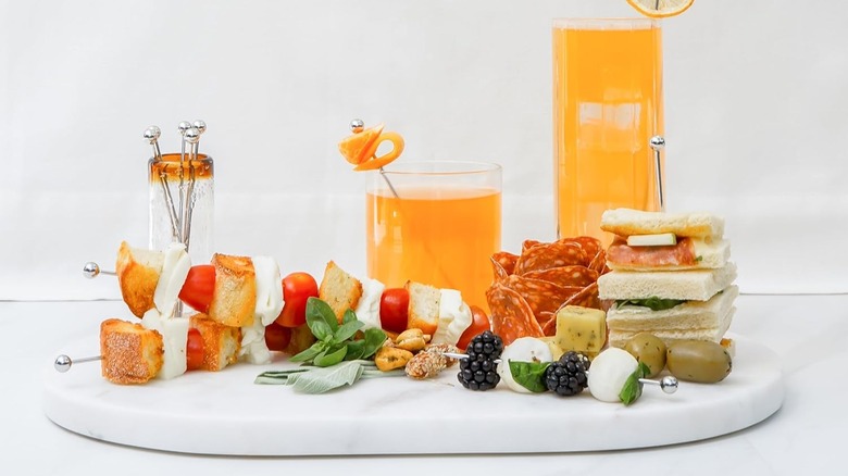 Drinks with speared garnishes along with snack skewers.