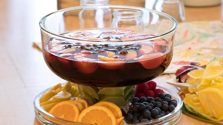 A punch bowl holds red sangria with lots of fruit.