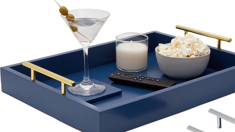 A tray holds a martini with olives, a candle, popcorn, and a remote control.