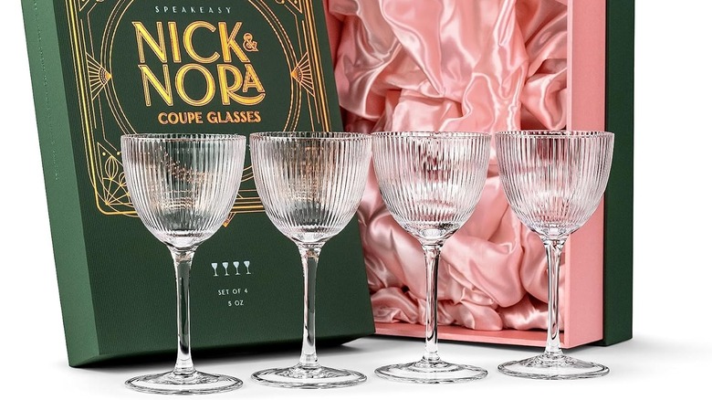 A set of four Nick and Nora glasses in front of a green gift box.