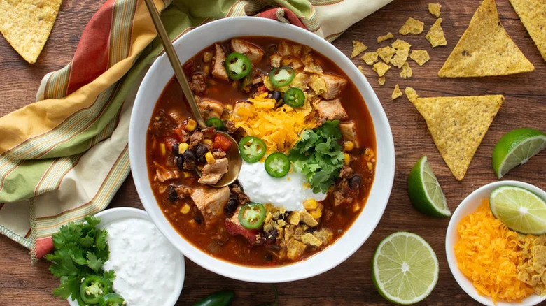 A bowl of High-Protein Tex Mex Soup with fresh toppings and tortilla chips