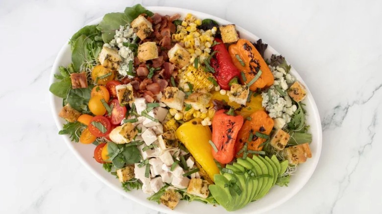 Overhead view of a large serving dish of rotisserie chicken salad with lots of veggies