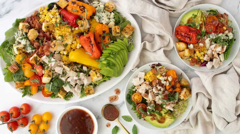 A large dish and smaller bowls of Rotisserie Chicken Salad With Hot Bacon And Raspberry Dressing