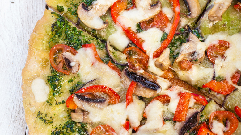 Spring Vegetable And Pesto Pizza on a wooden cutting board