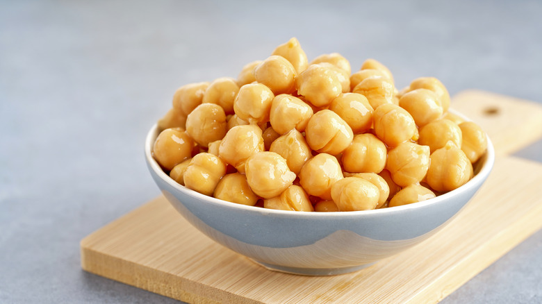 Chickpeas piled in a white ceramic bowl on a cutting board