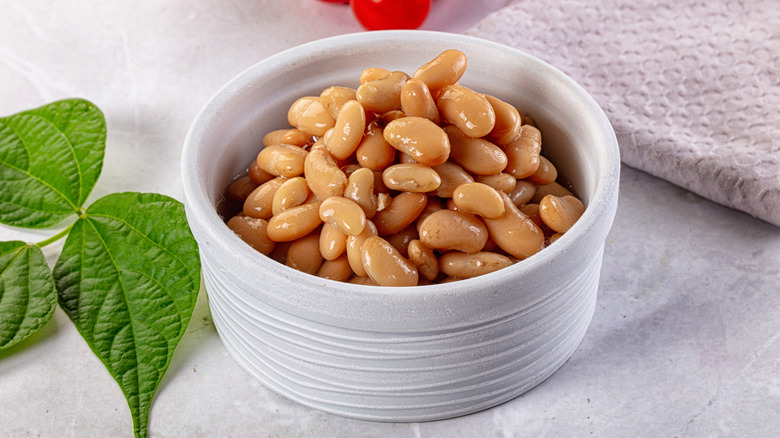 Beans in a white bowl with herbs on the side