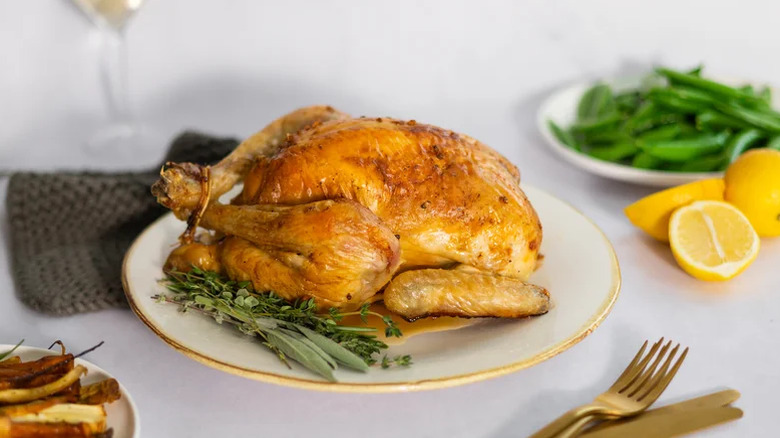 Roast chicken on a plate with lemons and greens