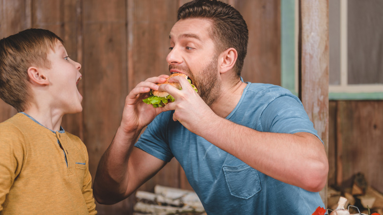 a father eating a burger with his son