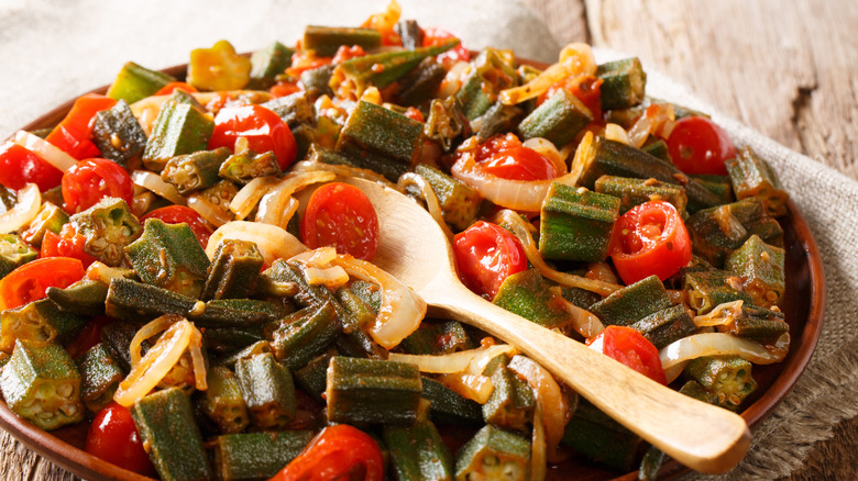 Okra and tomatoes in bowl with spoon