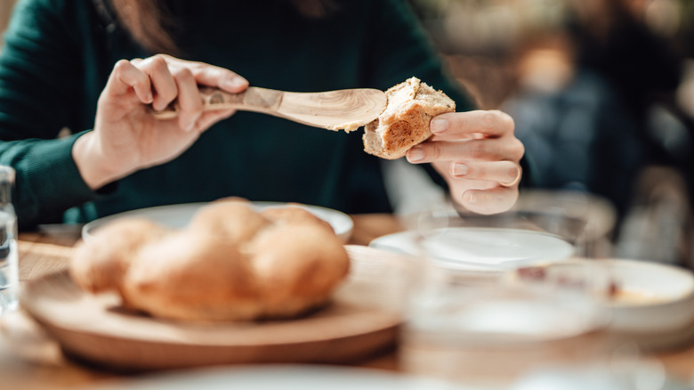 Woman spreading butter on a piece of bread