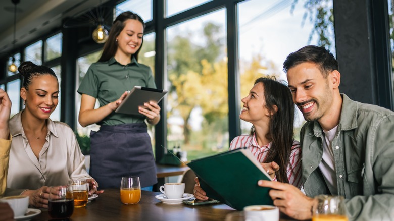 Group of friends ordering their meal from a waiter at a restaurant