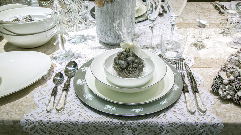 Elegant formal table setting with white plates and a snowflake-rimmed charger