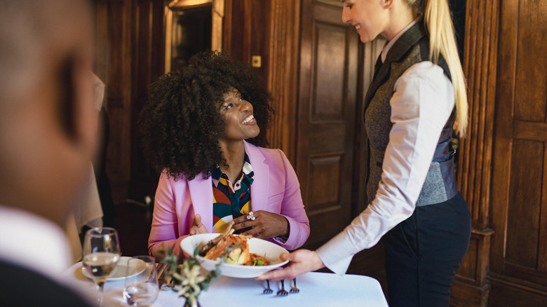 Waitress serving a meal to a woman in a restaurant