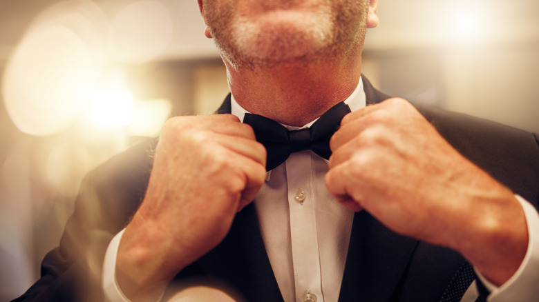 Man adjusting bowtie of formal tuxedo