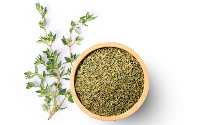 Sprigs of fresh thyme and wooden bowl of dried thyme