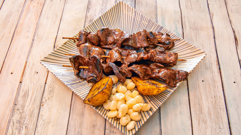 A plate of anticuchos with corn and potatoes