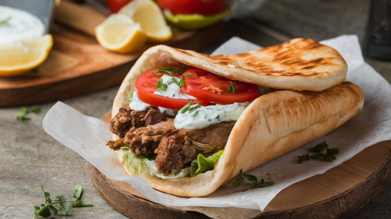 A lamb gyro on wax paper and a wooden cutting board