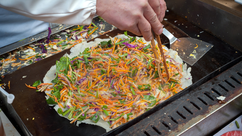 A person making jianbing on a griddle