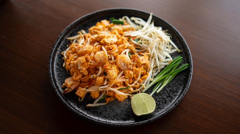 A plate of Pad Thai with bean sprouts, lime, and green onions