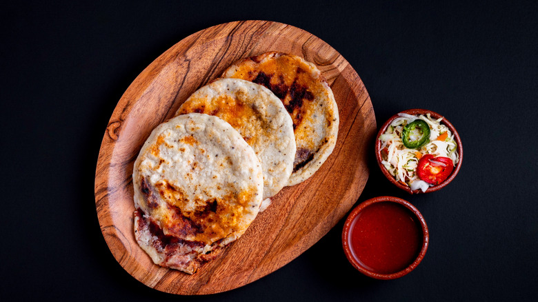 Three pupusas on a wooden plate