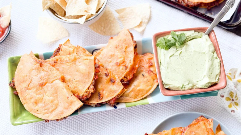 A platter of Baked Crispy Beef Tacos beside a dish of sauce