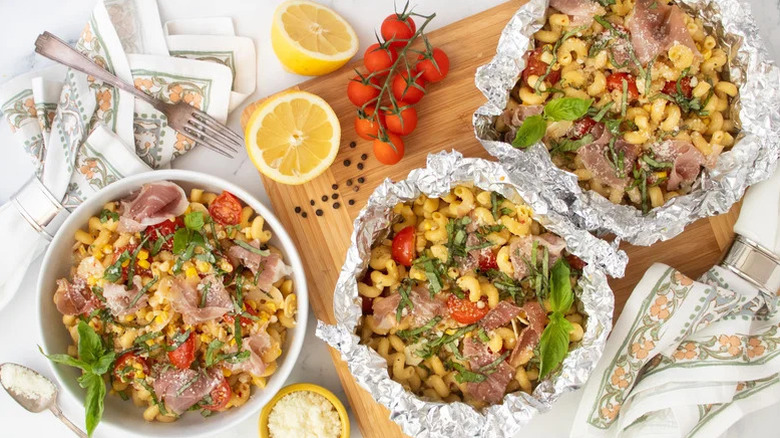 Packets of Foil Packet Summer Pasta with lemons and tomatoes beside them