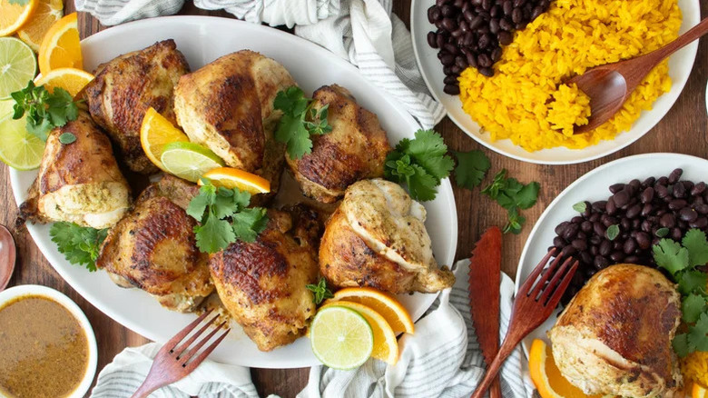 A platter of Pan-Seared Cuban Mojo Chicken with rice and beans beside it