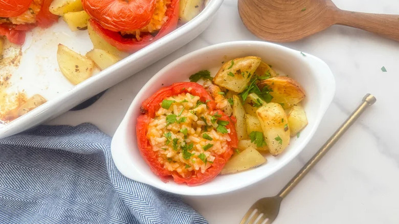 A casserole and dish of Pomodori Con Riso (Roman Baked Stuffed Tomatoes)