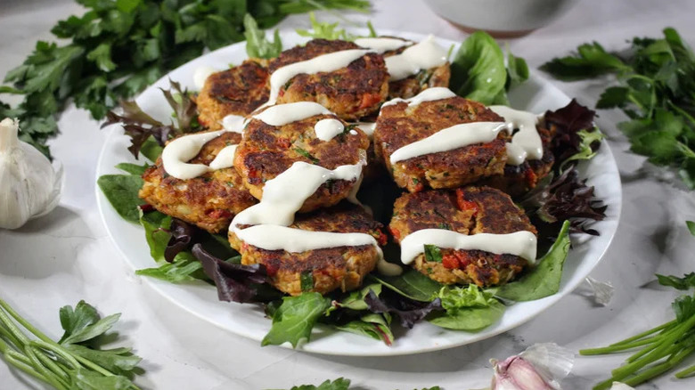 A platter of Spanish-Inspired Tuna Patties And Shortcut Aioli with greens around it
