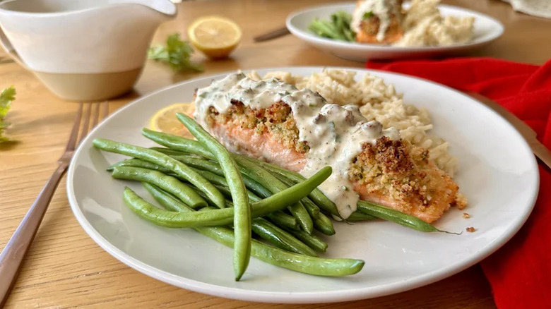 Parmesan-crusted salmon with creamy herb sauce served on a white plate