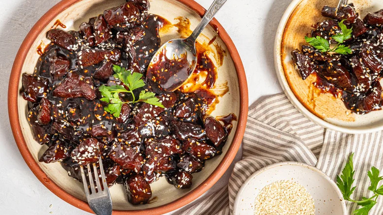Sticky soy steak bites with a fork and spoon resting on plate